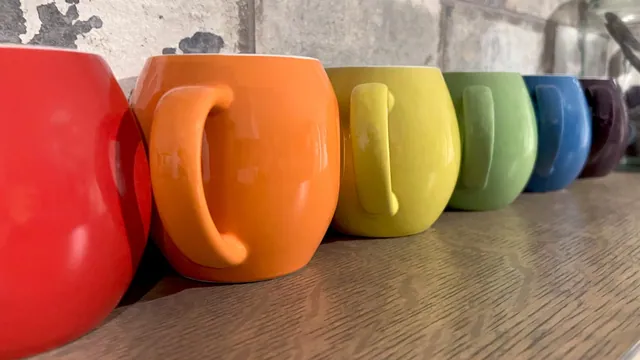 Row of ceramic mugs in red, orange, yellow and green