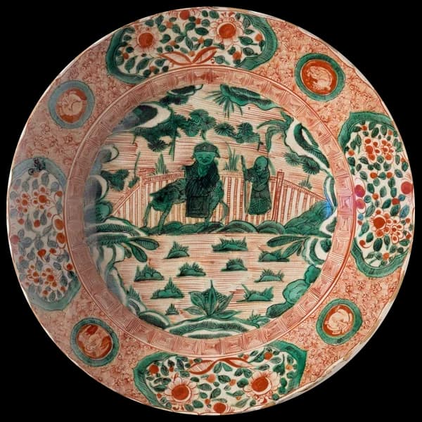Plate with a green landscape inside a red patterned border