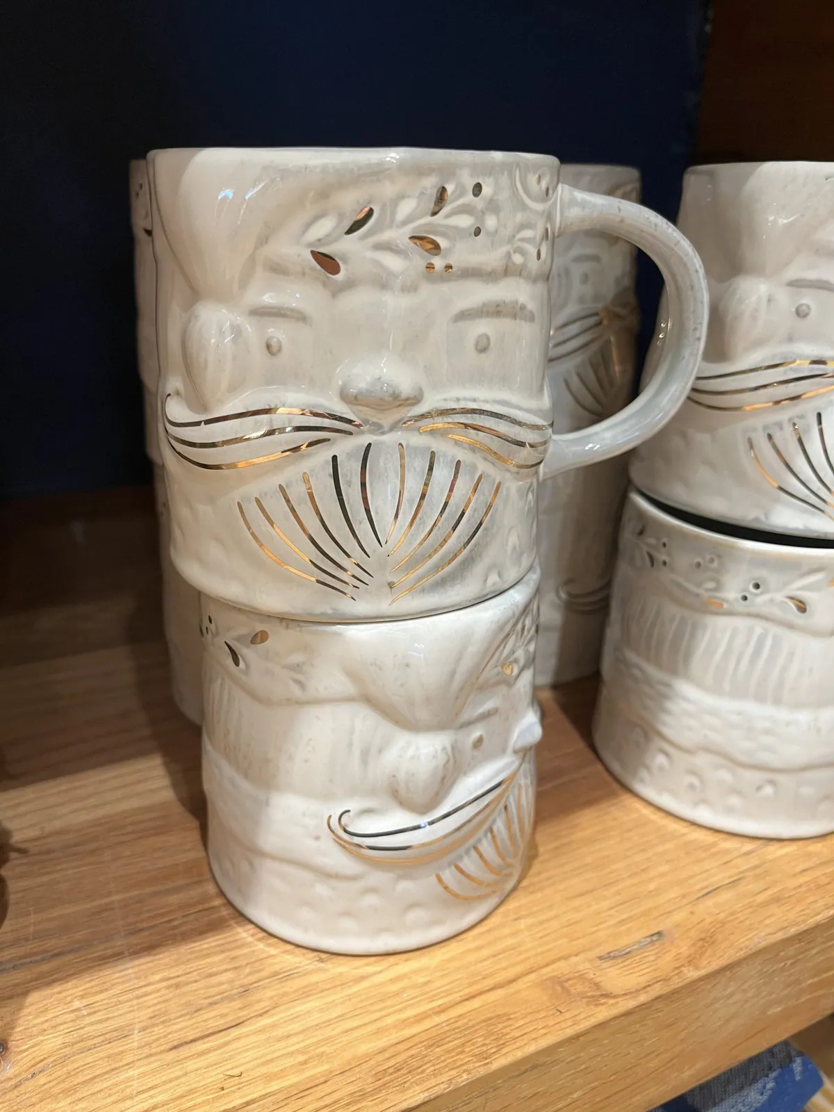 Carved white ceramic mugs on a shelf